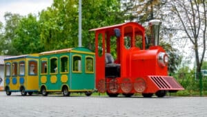 red steam locomotive with wagons, a children's attraction in an amusement park close-up against the background of green trees